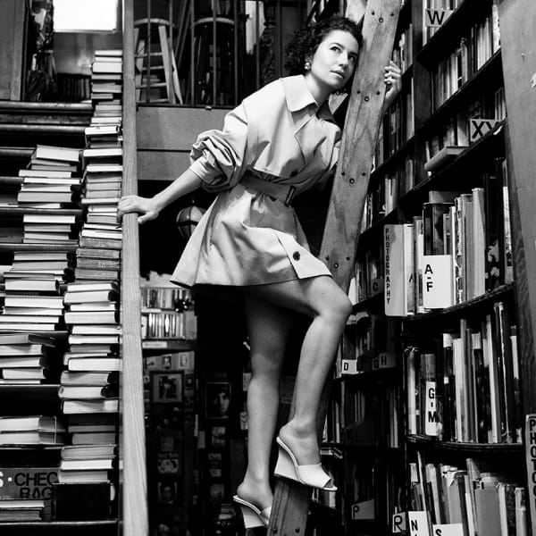 Stuart Weitzman Brand women standing on a library ladder showing off brand wedges